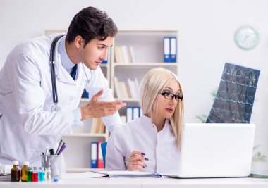 İki doktor teşhis için hastanın röntgen görüntülerini inceliyor.