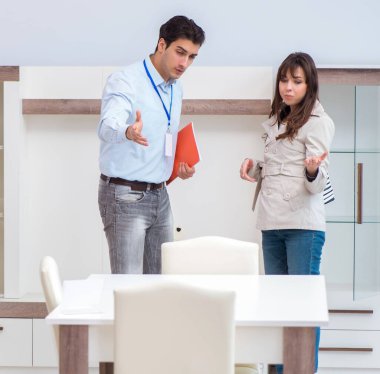 Satıcı mobilya dükkanındaki kadın müşteriye açıklama yapıyor.