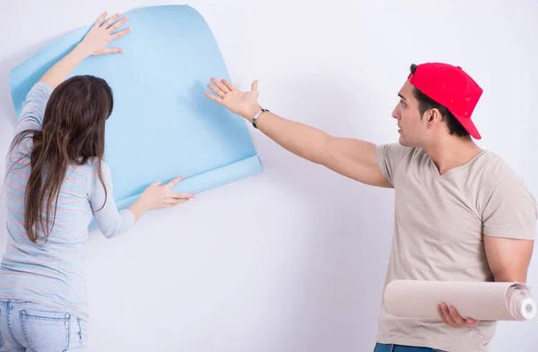 A jovem família fazendo renovação em casa com novo papel de parede — Fotografia de Stock