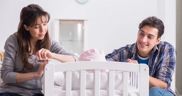 A fiatal szülők újszülött kisbabájukkal az ágy mellett — Stock Fotó