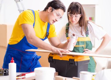 Ahşap atölyesinde kadınların ahşap işçiliğini açıklayan adam.