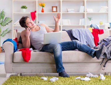 Genç adam dağınık bir odada çalışıyor.