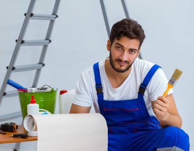 Tamirci, duvar kağıdıyla evde tadilat yapıyor.