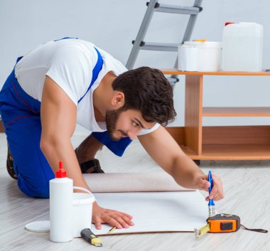 Tamirci, duvar kağıdıyla evde tadilat yapıyor.