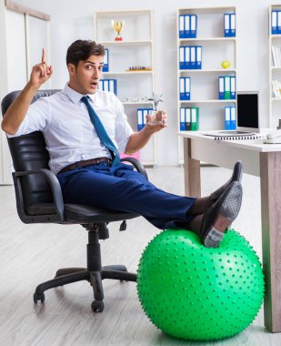 Genç işadamı iş yerinde spor yapıyor.