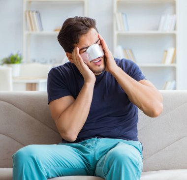 Genç adam estetik cerrahi burnundan sonra evde iyileşiyor.