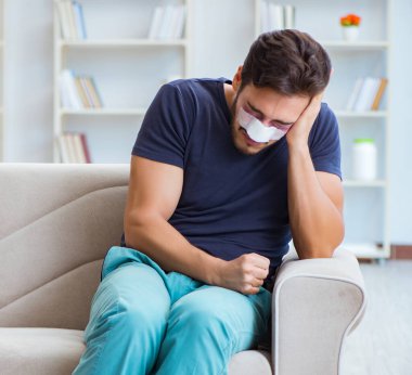 Genç adam estetik cerrahi burnundan sonra evde iyileşiyor.