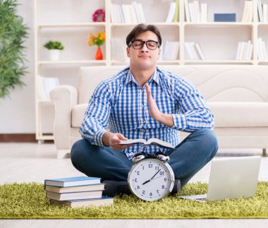 Genç yakışıklı adam evde yerde oturuyor.