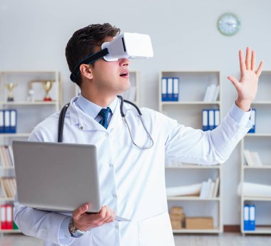 Sanal gerçeklik kulaklığı olan genç doktor ofiste çalışıyor.