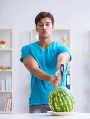 Evde karpuz yiyen bir adam.