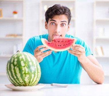 Evde karpuz yiyen bir adam.