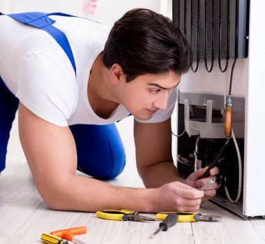 Tamirci müteahhit DIY konseptinde buzdolabını tamir ediyor.