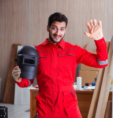 Kaynak tabancası elektrot ve kask takan genç bir tamirci.