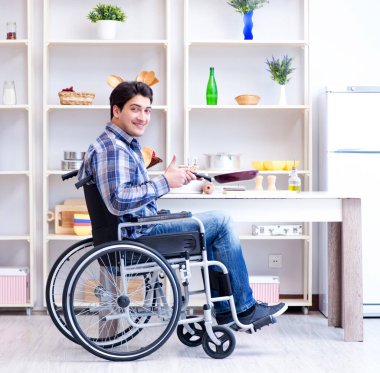 Engelli genç koca mutfakta çalışıyor.