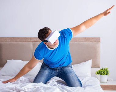 Yatakta sanal gerçeklik başlığı takan genç bir adam.