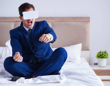 Yatak odasında sanal gerçeklik kulaklığı takan bir iş adamı.