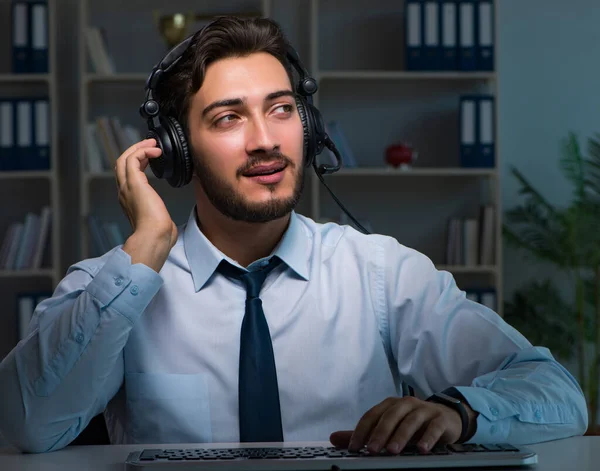 Młody człowiek w koncepcji call center pracuje do późna nadgodziny w biurze — Zdjęcie stockowe