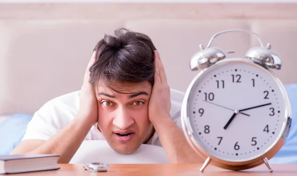 Hombre en la cama frustrado sufriendo de insomnio con un zueco de alarma — Foto de Stock