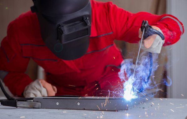 Young repairman with a welding gun electrode and a helmet weldin