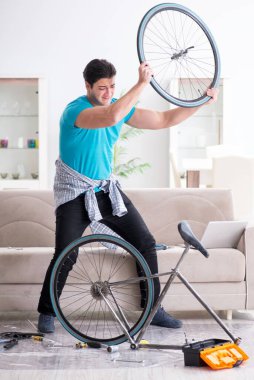 Evde bisiklet tamir eden genç bir adam.