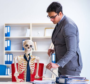 İskeletle çalışan bir iş adamı.