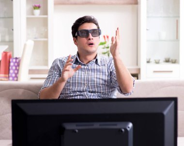 Evde 3D televizyon izleyen bir adam.