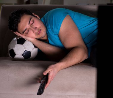 Genç adam gece geç saatlerde futbol seyrediyor.