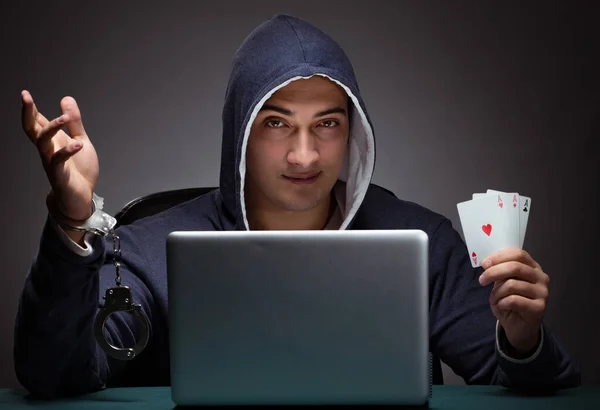 Giovane uomo in manette che indossa una felpa con cappuccio seduto di fronte a un la — Foto Stock