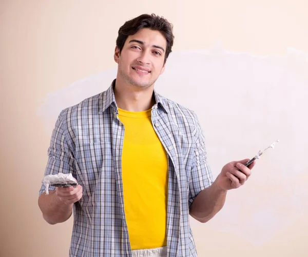 Young man applying plaster on wall at home — Stock Photo, Image