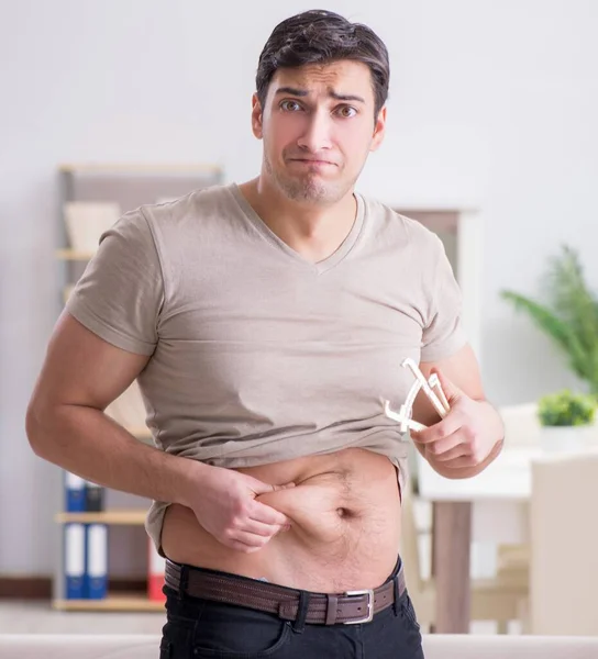 Uomo che misura il grasso corporeo con pinze — Foto Stock