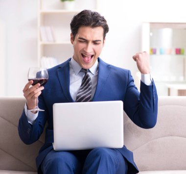 İş adamı evde oturmuş şarap içiyor.