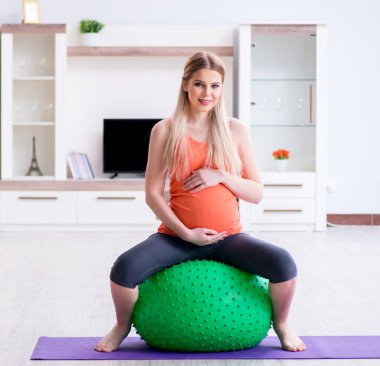 Evde doğum egzersizi yapmaya hazırlanan genç bir kadın.