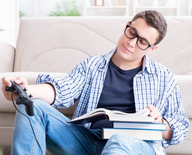 Çalışmayı ve oyun oynamayı dengelemeye çalışan genç öğrenci