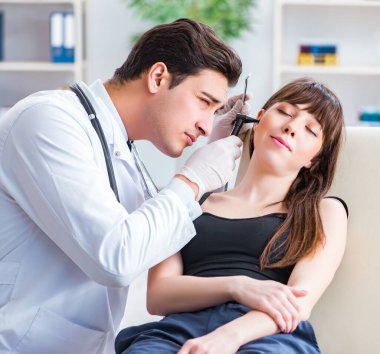 Doktor muayene sırasında hastaların kulaklarını kontrol ediyor.