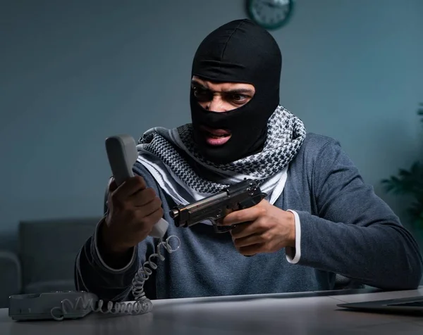 Terrorist burglar with gun working at computer — Stock Photo, Image