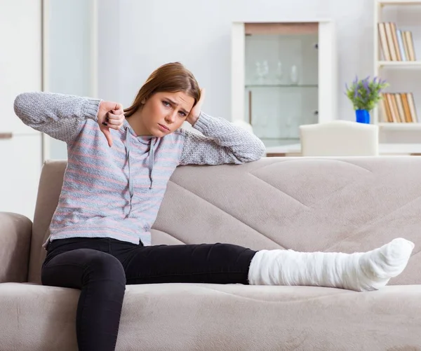 Junge Frau mit gebrochenem Bein zu Hause — Stockfoto