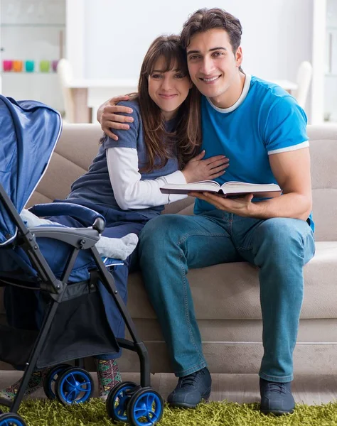 Mladí rodiče se svým novorozeným dítětem v kočárku sedí na — Stock fotografie