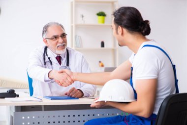 Genç erkek müteahhit yaşlı doktoru ziyaret ediyor.