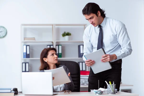 Alte weibliche Chefin und junge männliche Angestellte im Büro — Stockfoto