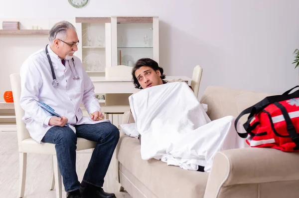Старий лікар відвідує молодого пацієнта чоловічої статі — стокове фото