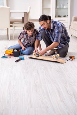 Genç baba oğluyla kaykay tamir ediyor.