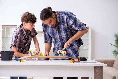 Genç baba oğluyla kaykay tamir ediyor.