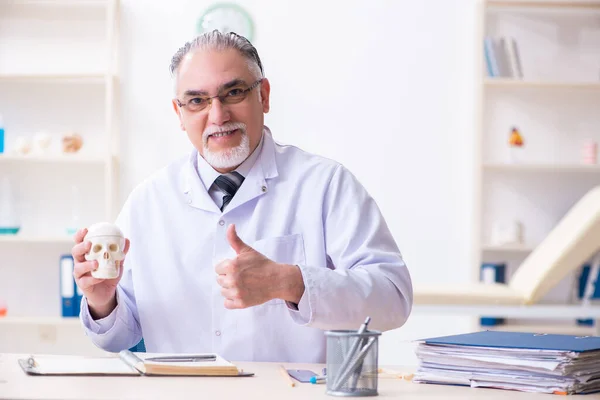 Åldrad manlig läkare med skelett — Stockfoto