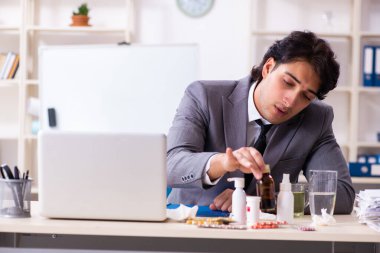 Ofiste grip olmuş bir adam çalışıyor.