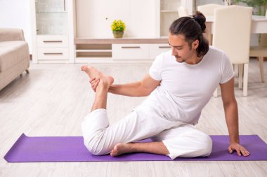 Genç adam evde fiziksel egzersiz yapıyor.