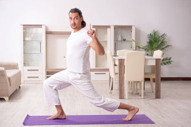 Genç adam evde fiziksel egzersiz yapıyor.