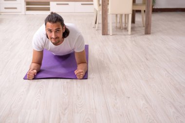 Genç adam evde fiziksel egzersiz yapıyor.