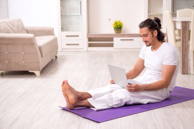 Genç adam evde fiziksel egzersiz yapıyor.