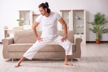 Genç adam evde fiziksel egzersiz yapıyor.