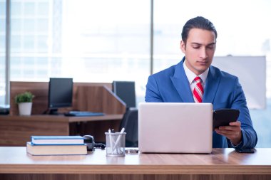 Genç yakışıklı işadamı ofiste oturuyor.